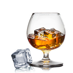 Image showing Splash of whiskey with ice in glass isolated on white
