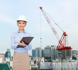 Image showing smiling businesswoman in helmet with clipboard