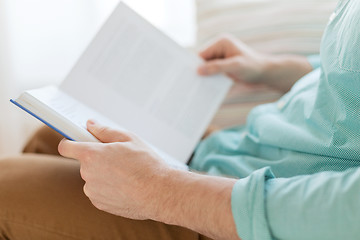 Image showing close up of man reading book at home