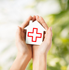 Image showing hands holding paper house with red cross