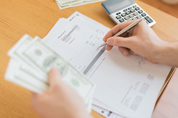 Image showing close up of man counting money and making notes