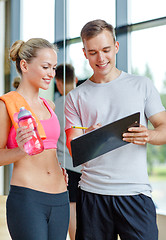 Image showing smiling young woman with personal trainer in gym