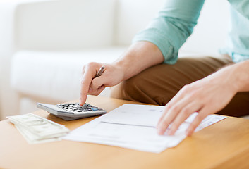 Image showing close up of man counting money and making notes