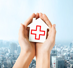 Image showing hands holding paper house with red cross