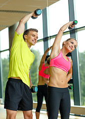 Image showing smiling man and woman with dumbbells in gym