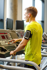 Image showing man with smartphone exercising on treadmill in gym