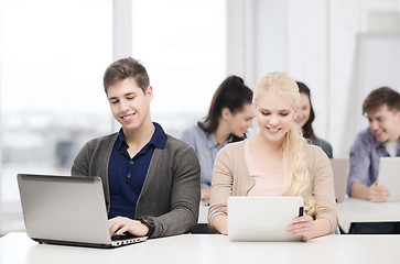 Image showing two smiling students with laptop and tablet pc