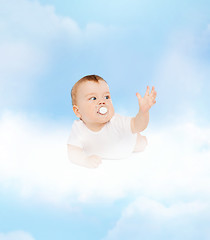 Image showing smiling baby lying on cloud with dummy in mouth