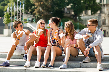 Image showing group of smiling friends sitting on city square