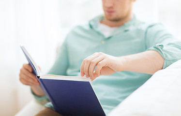 Image showing close up of man reading book at home