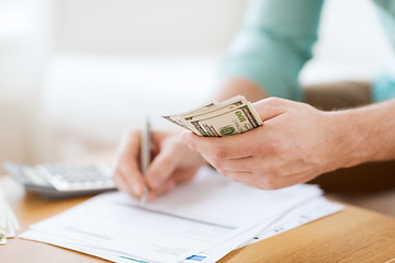 Image showing close up of man counting money and making notes