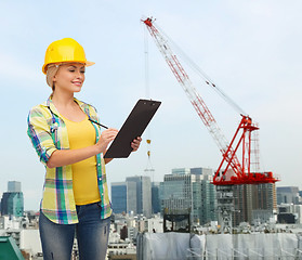 Image showing smiling woman in helmet with clipboard