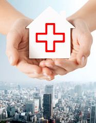 Image showing hands holding paper house with red cross