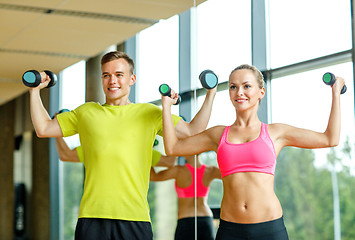 Image showing smiling man and woman with dumbbells in gym