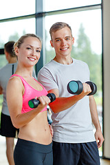 Image showing smiling young woman with personal trainer in gym