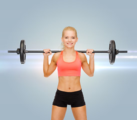 Image showing smiling sporty woman exercising with barbell