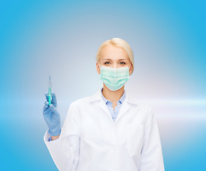 Image showing doctor in mask holding syringe with injection
