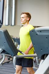 Image showing man with smartphone exercising on treadmill in gym