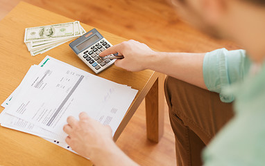 Image showing close up of man counting money and making notes