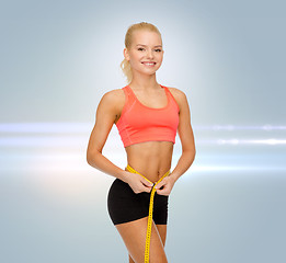 Image showing smiling sporty woman with measuring tape