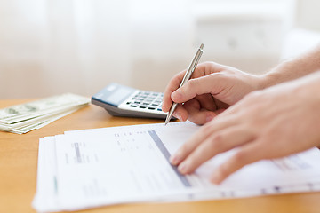 Image showing close up of man counting money and making notes