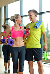 Image showing smiling couple with water bottles in gym