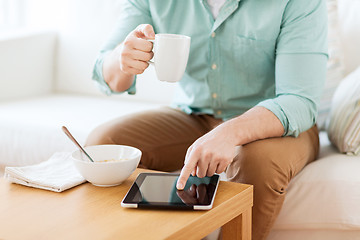 Image showing close up of man with tablet pc having breakfast