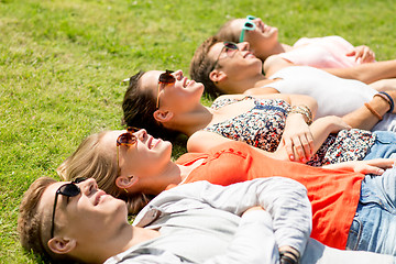 Image showing group of smiling friends lying on grass outdoors