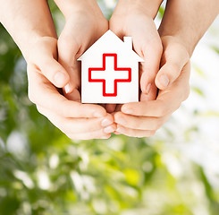Image showing hands holding paper house with red cross