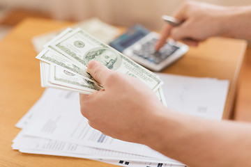 Image showing close up of man counting money and making notes