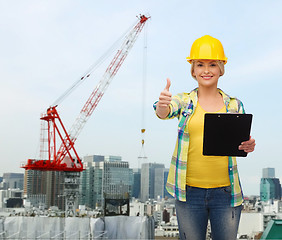 Image showing smiling woman in helmet with clipboard