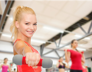 Image showing smiling beautiful sporty woman with dumbbell