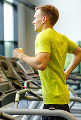 Image showing smiling man exercising on treadmill in gym