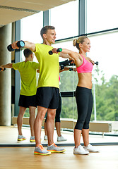 Image showing smiling man and woman with dumbbells in gym