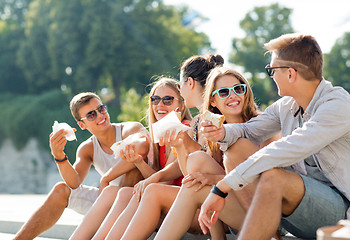 Image showing group of smiling friends sitting on city square