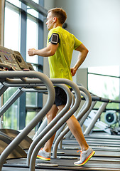 Image showing man with smartphone exercising on treadmill in gym