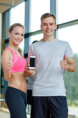 Image showing smiling young woman with personal trainer in gym