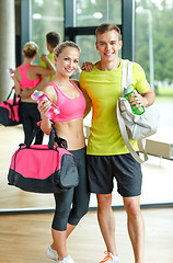 Image showing smiling couple with water bottles in gym
