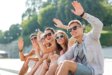 Image showing group of smiling friends sitting on city street