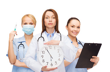 Image showing calm female doctor and nurses with wall clock
