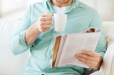 Image showing close up of man with magazine drinking from cup