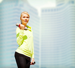 Image showing sporty woman with light dumbbells outdoors