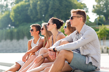 Image showing group of smiling friends sitting on city square