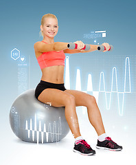 Image showing woman with dumbbells sitting on fitness ball