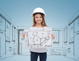 Image showing smiling little girl in helmet showing blueprint