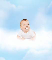 Image showing smiling baby lying on cloud with dummy in mouth