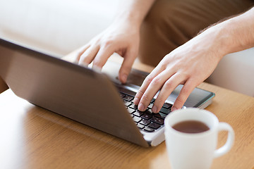 Image showing close up of man with laptop and cup at home