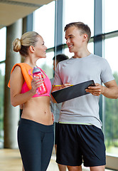 Image showing smiling young woman with personal trainer in gym