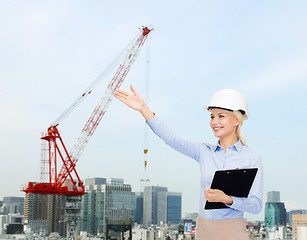 Image showing smiling businesswoman in helmet with clipboard