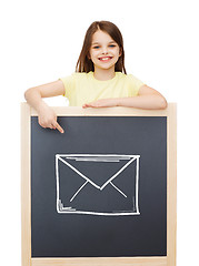 Image showing smiling little girl pointing finger to blackboard